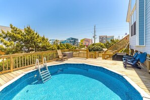 Ein Swimmingpool mit Holzterrasse, einer Treppe und einer Liegefläche mit Stühlen.