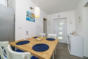 Eine moderne Küche mit weißen Geräten, einem Holztisch mit blauen Tischsets und einem Bild an der Wand.