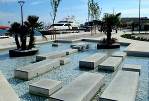 A marina with yachts docked, a swimming pool with concrete steps, and palm trees. - 201 luxury attic room in the heart of Split with roof terrace (Split)
