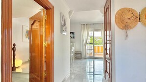 A hallway with a wooden door, a staircase, and a view of the outside. - TERRASOL LOS NARDOS 229 (Caleta de velez)