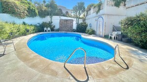 A swimming pool with a stone wall and a small patio area. - TERRASOL LOS NARDOS 229 (Caleta de velez)