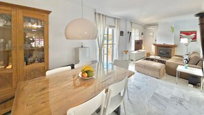 A dining area with a wooden table and chairs, a modern pendant light, and a fruit bowl. - TERRASOL LOS NARDOS 229 (Caleta de velez)