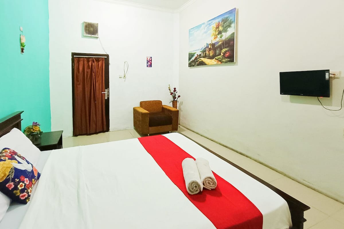 Een hotelkamer met een bed, een stoel, een schilderij aan de muur en een televisie.
