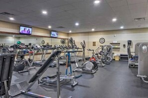 Ein Fitnessstudio mit verschiedenen Trainingsgeräten, darunter Laufbänder, Ergometer und Kraftgeräte.