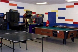 Ein Spielraum mit Billardtisch, Spielautomaten und Dartscheibe.
