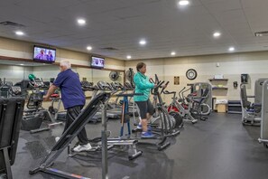 Un gimnasio con cintas de correr, bicicletas estáticas y máquinas de pesas.
