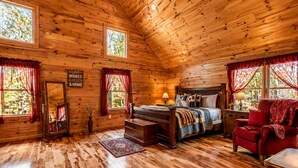 A log cabin bedroom with a bed, dresser, chair, and a mirror. - Rustic Cabin Getaway with Cozy Charm & Serene Surroundings in Gilmer County, Georgia (Gilmer County)