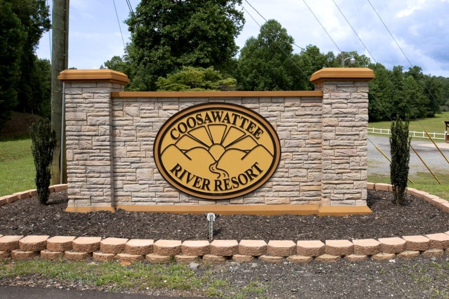 Un mur de pierre sur lequel est apposé un panneau circulaire indiquant « Coosawattee River Resort ».