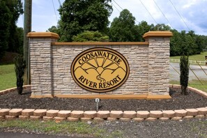 Un muro de piedra con un letrero circular para Coosawattee River Resort.