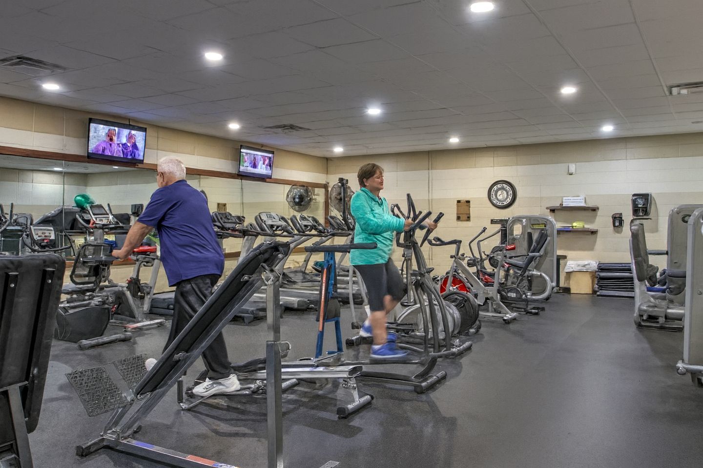 Une salle de sport équipée de tapis de course, de vélos d’appartement et d’appareils de musculation.