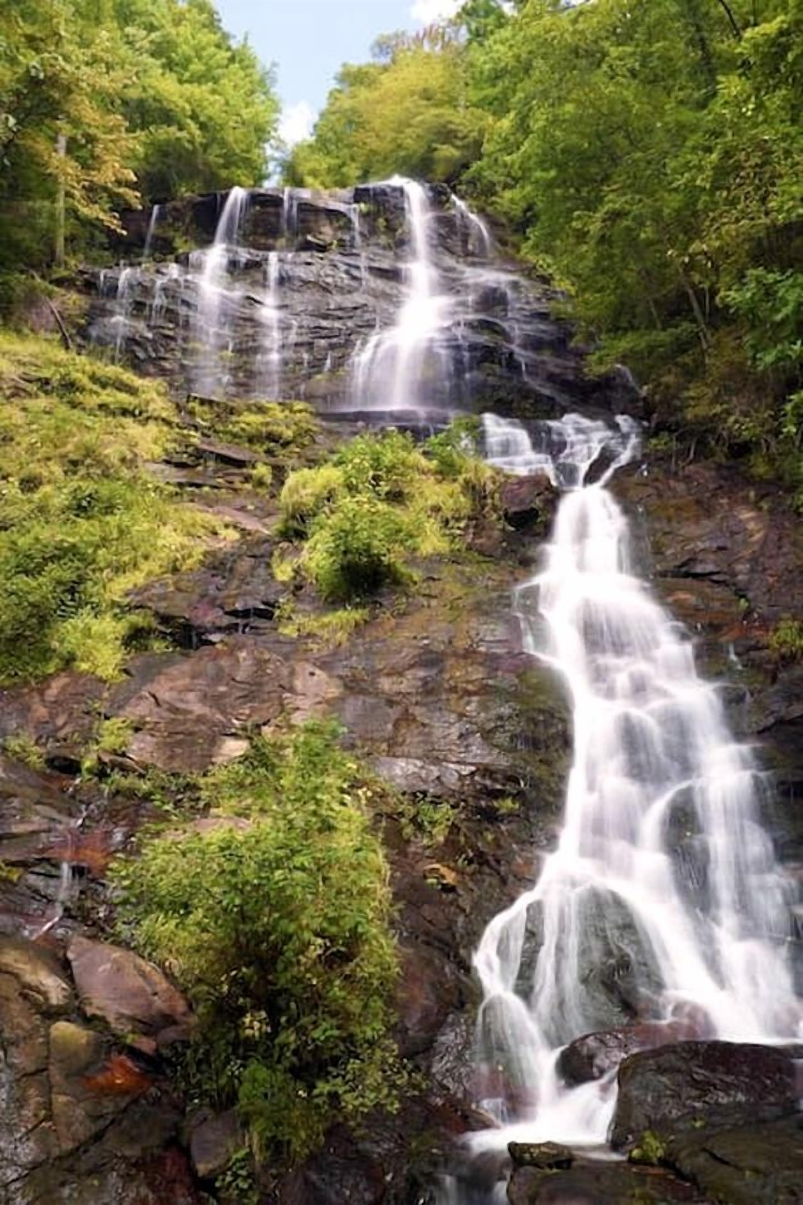 A waterfall cascading over rocky terrain surrounded by lush greenery.