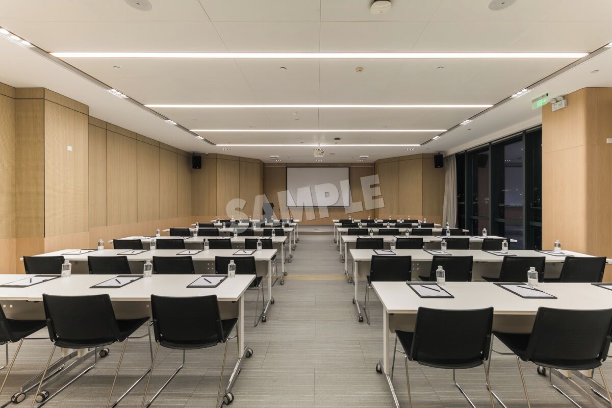 A conference room with multiple tables and chairs, equipped with water bottles and nameplates.