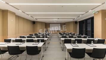 A conference room with multiple tables and chairs, equipped with water bottles and nameplates.