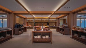 A modern hotel lobby with a central buffet, wooden furniture, and a high ceiling with recessed lighting. - IntercityHotel Zhuhai Hengqin Tianmu River (Zhuhai)