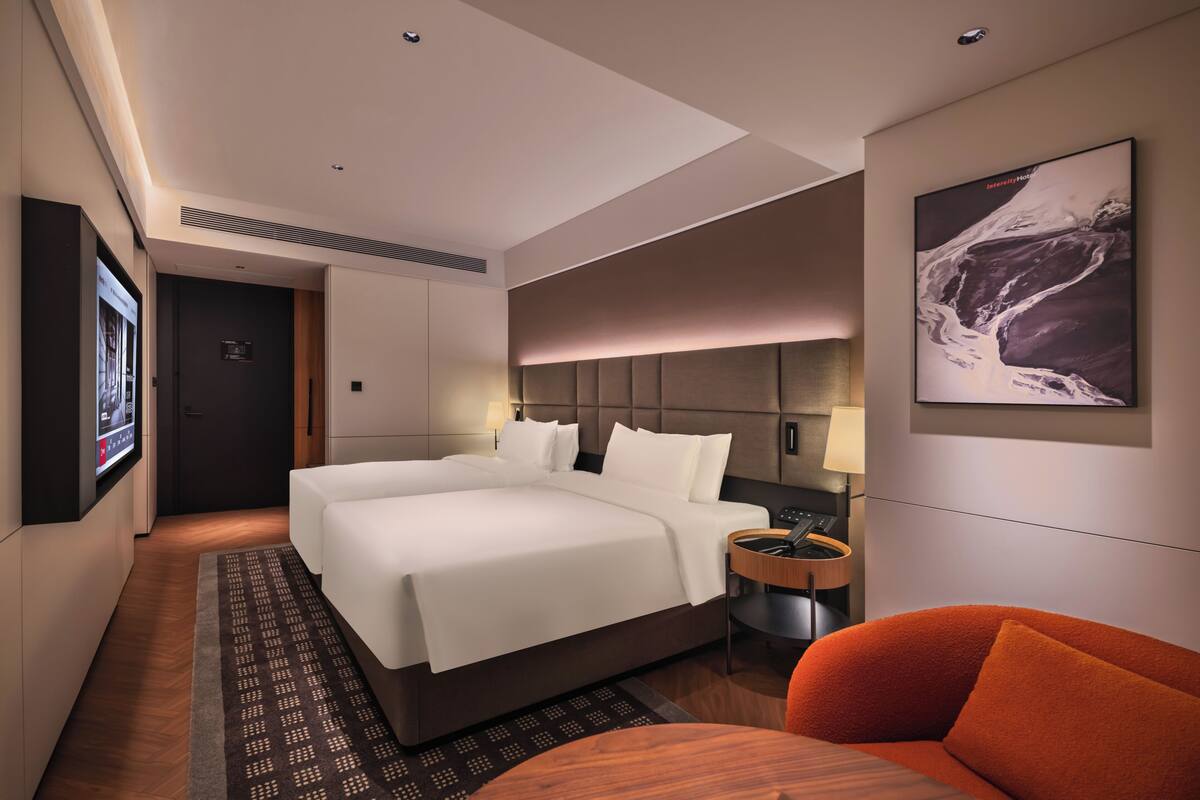 Ein Hotelzimmer mit einem großen Bett, einem Schreibtisch, einem Sessel, einem Fernseher und einem Bild an der Wand.