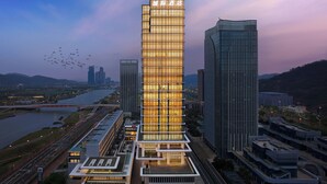 A modern hotel with a prominent vertical facade, a rooftop terrace, and a view of a river and cityscape. - IntercityHotel Zhuhai Hengqin Tianmu River (Zhuhai)