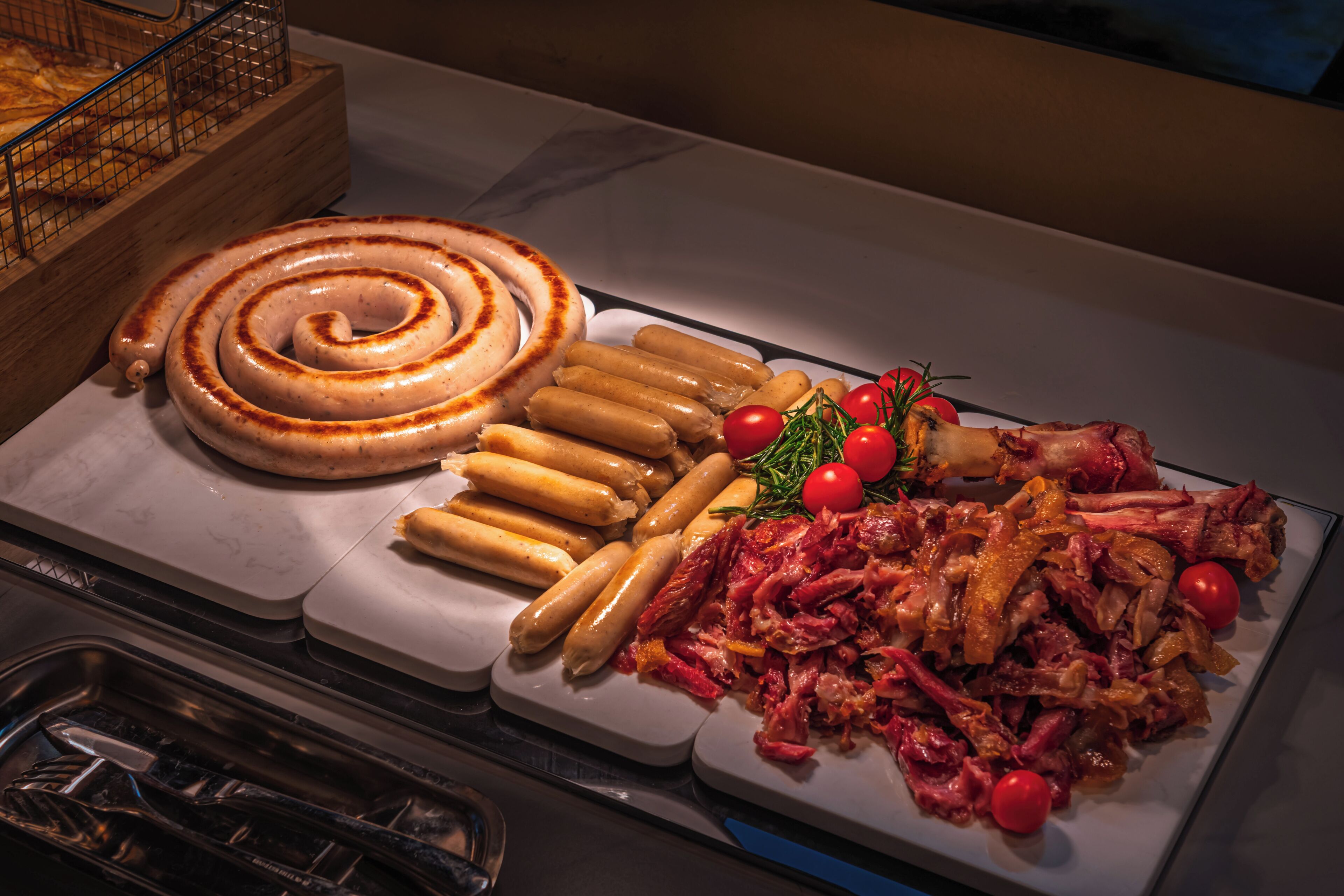 A buffet with various meats, sausages, and garnishes.