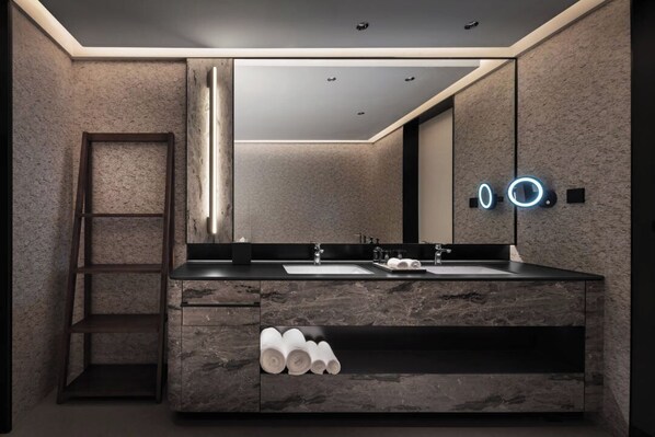 A modern bathroom with a marble vanity, a large mirror, and a towel rack.
