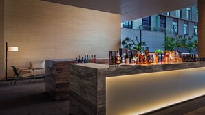 A modern bar area with a marble counter, various bottles, and a seating area with a chair. - IntercityHotel Zhuhai Hengqin Tianmu River (Zhuhai)