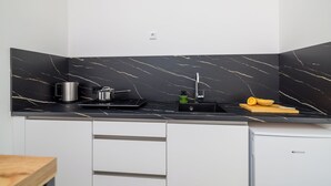 Una cocina moderna con salpicadero de mármol negro, un fregadero y un lavavajillas compacto.