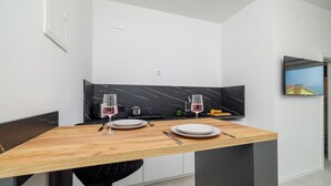 Una cocina moderna con una mesa de madera preparada para dos personas, un salpicadero de mármol negro y un televisor de pantalla plana montado en la pared.