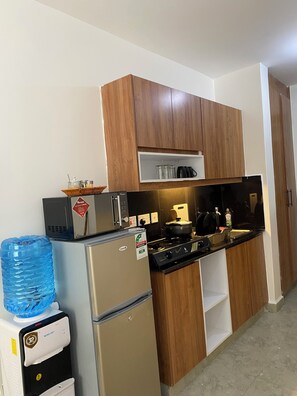 Eine kleine Küche mit Holzausstattung, einem Edelstahlkühlschrank, einem Wasserspender und einem Herd.