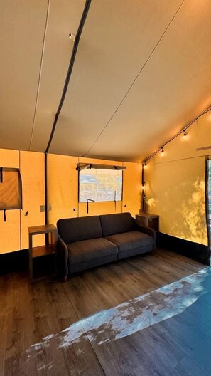 Una habitación acogedora con sofá, una mesita, ventana con vistas y un proyector montado en la pared.