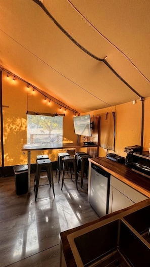 A compact kitchen with a dining area, a projector screen, and a small trash bin.