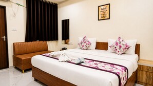 A hotel room with a bed, a sofa, a mirror, a wall clock, and a framed quote. - The Cressida Hotel (Indore)