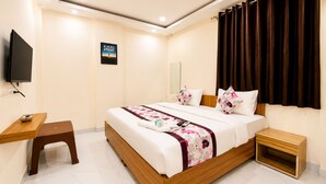 A hotel room with a bed, bedside table, nightstand, and a television mounted on the wall. - The Cressida Hotel (Indore)