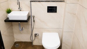 A bathroom with a white sink, a toilet, and a shower. - The Cressida Hotel (Indore)