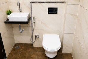 Une salle de bain avec un lavabo blanc, des toilettes et une douche.