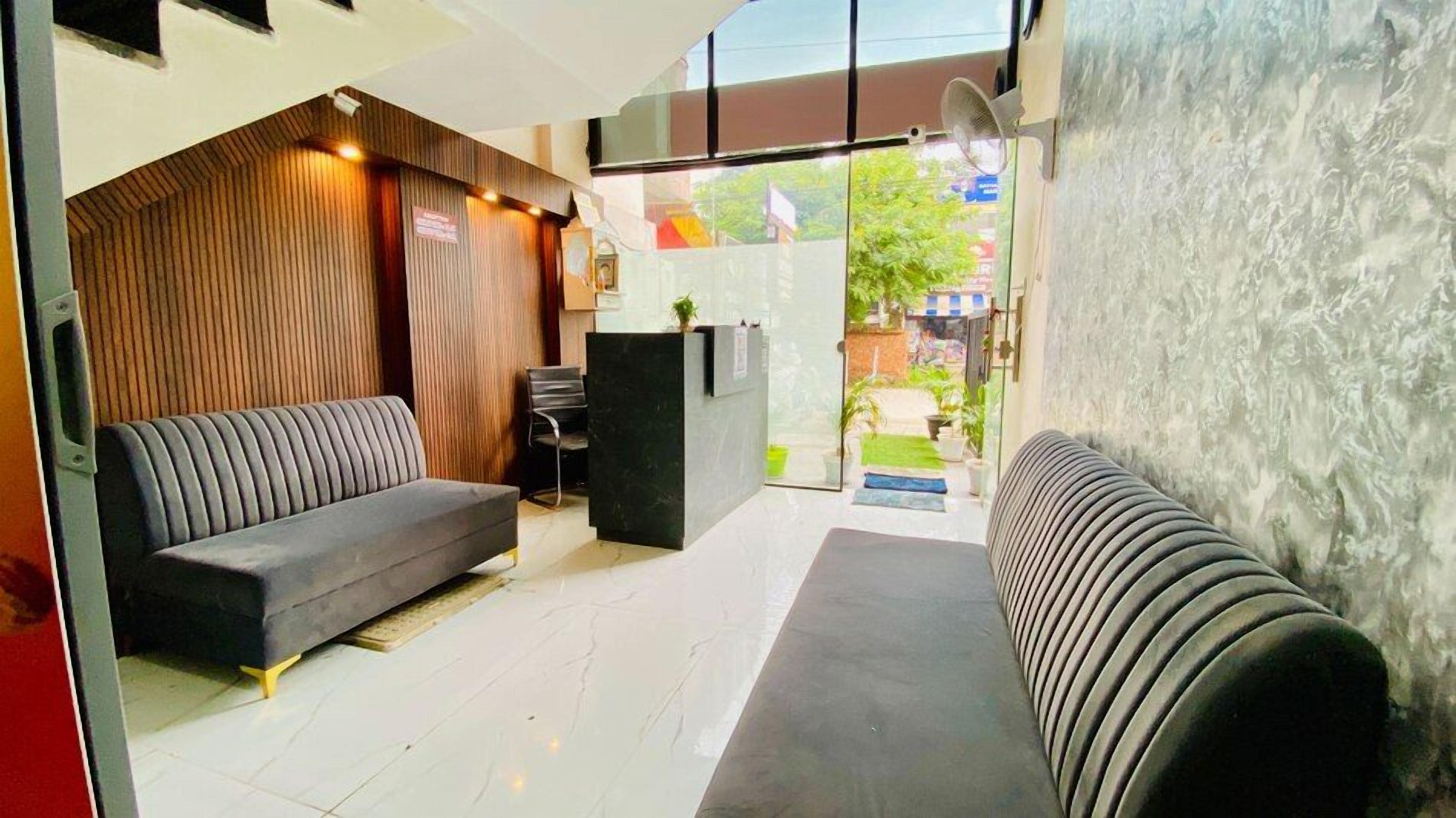 A reception area with a sofa, a reception desk, and a view of the outside.