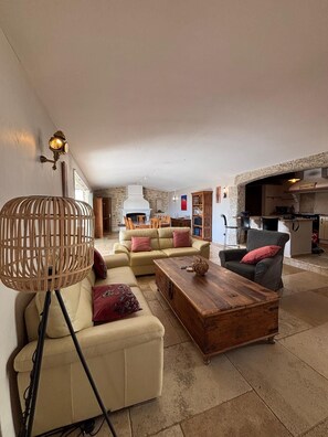 Ein geräumiger Wohnbereich mit einer Couch, einem Holztisch, einer Korbtischlampe und einem Steinkamin.