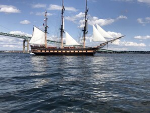 Un gran barco velero con varias mástiles y velas, amarrado cerca de un puente.