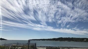Une plage avec un banc en bois, une clôture et un ciel dégagé.