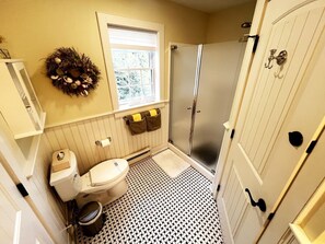 A bathroom with a toilet, a shower, a sink, a window, and a door. - Beautiful Cozy Cabin in Saunderstown, Rhode Island (Jamestown)