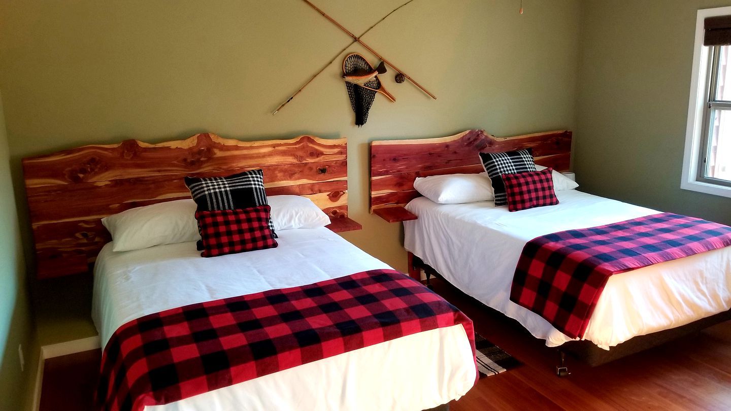 Two single beds with wooden headboards, white bedding, and red and black checkered blankets.