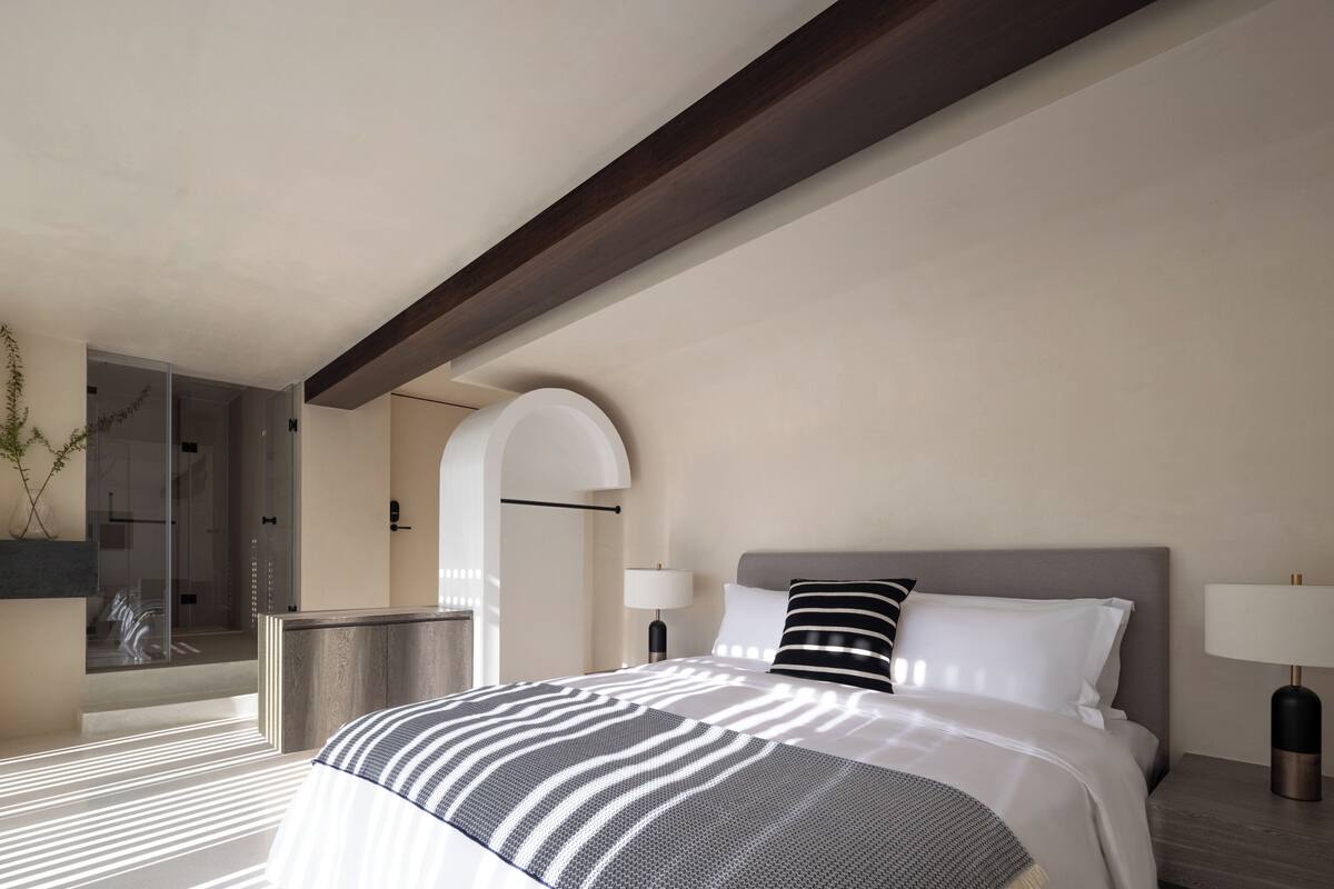 Ein modernes Hotelzimmer mit einem großen Bett, einem Nachttisch, einer Lampe und einer Dusche.
