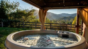 Un bain à remous extérieur avec vue sur les montagnes et les arbres.