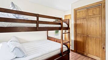 A bunk bed room with a wooden wardrobe and a window.