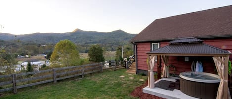 Une maison de campagne avec un jacuzzi et une terrasse couverte.