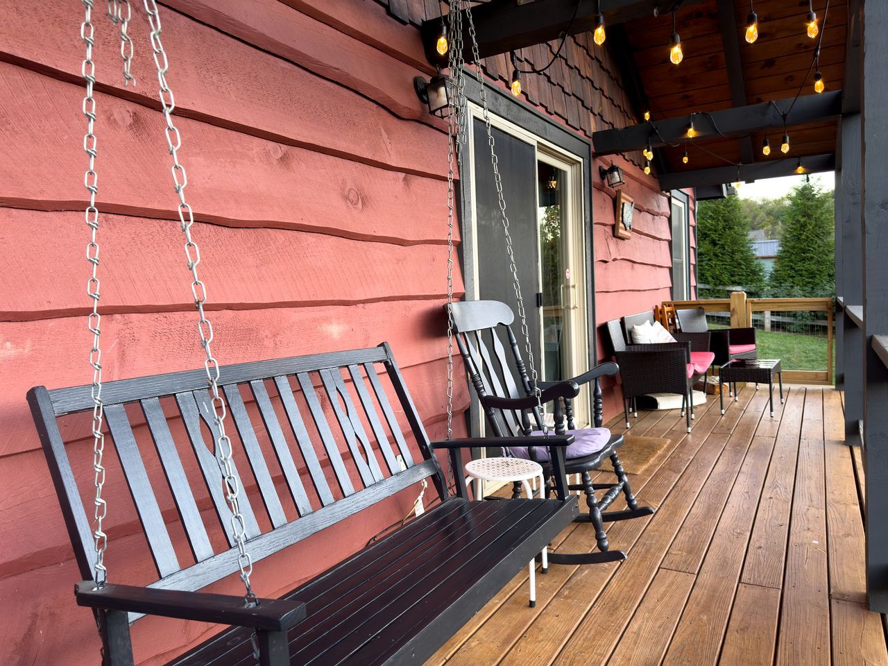 A wooden deck with a bench, chairs, and a table.