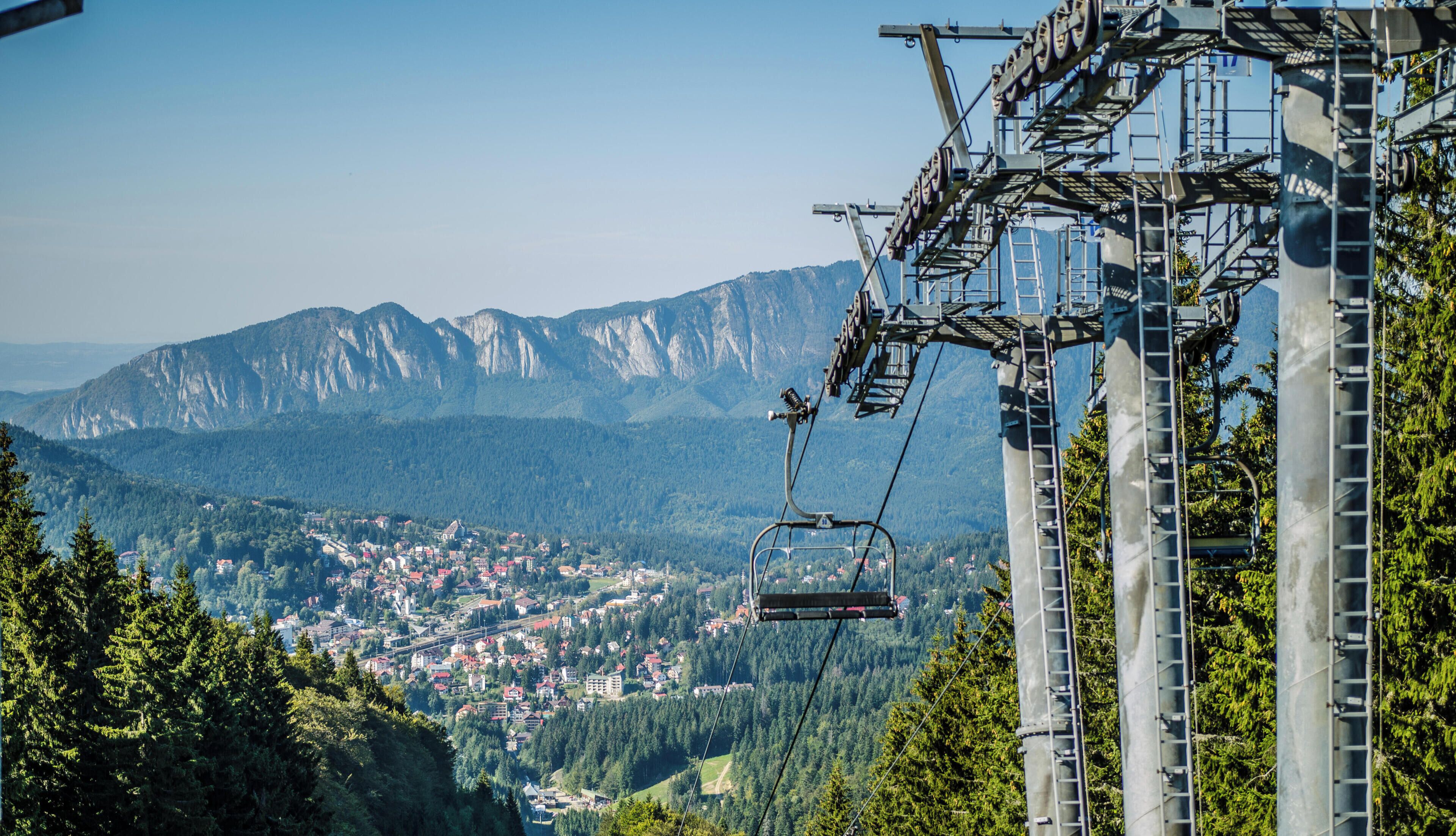 Un sistema de teleférico con montañas al fondo y un pueblo abajo.