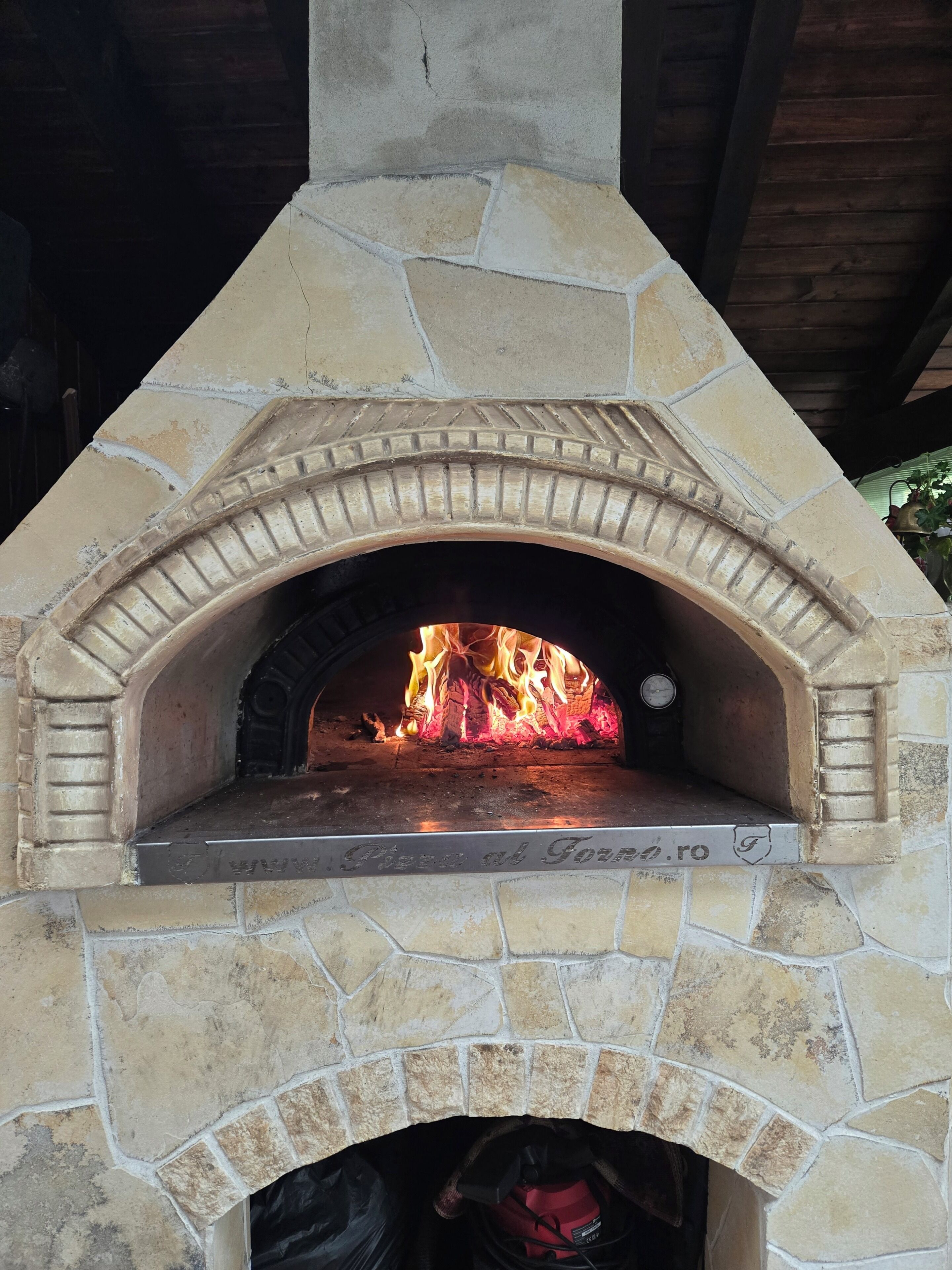 Un four à pizza extérieur en pierre, dans lequel brûle un feu.