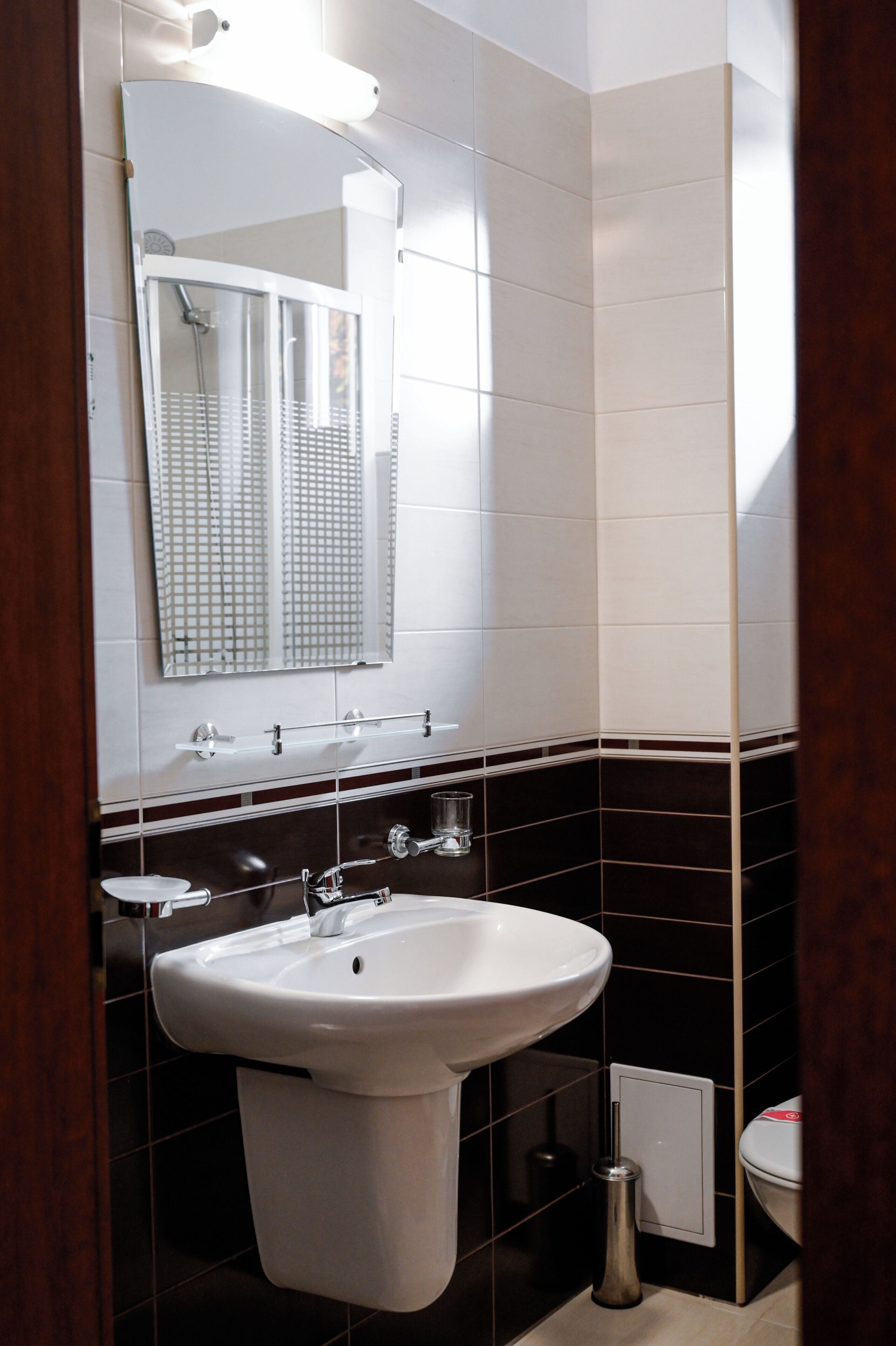 Un baño con lavamanos blanco, espejo y retrete.