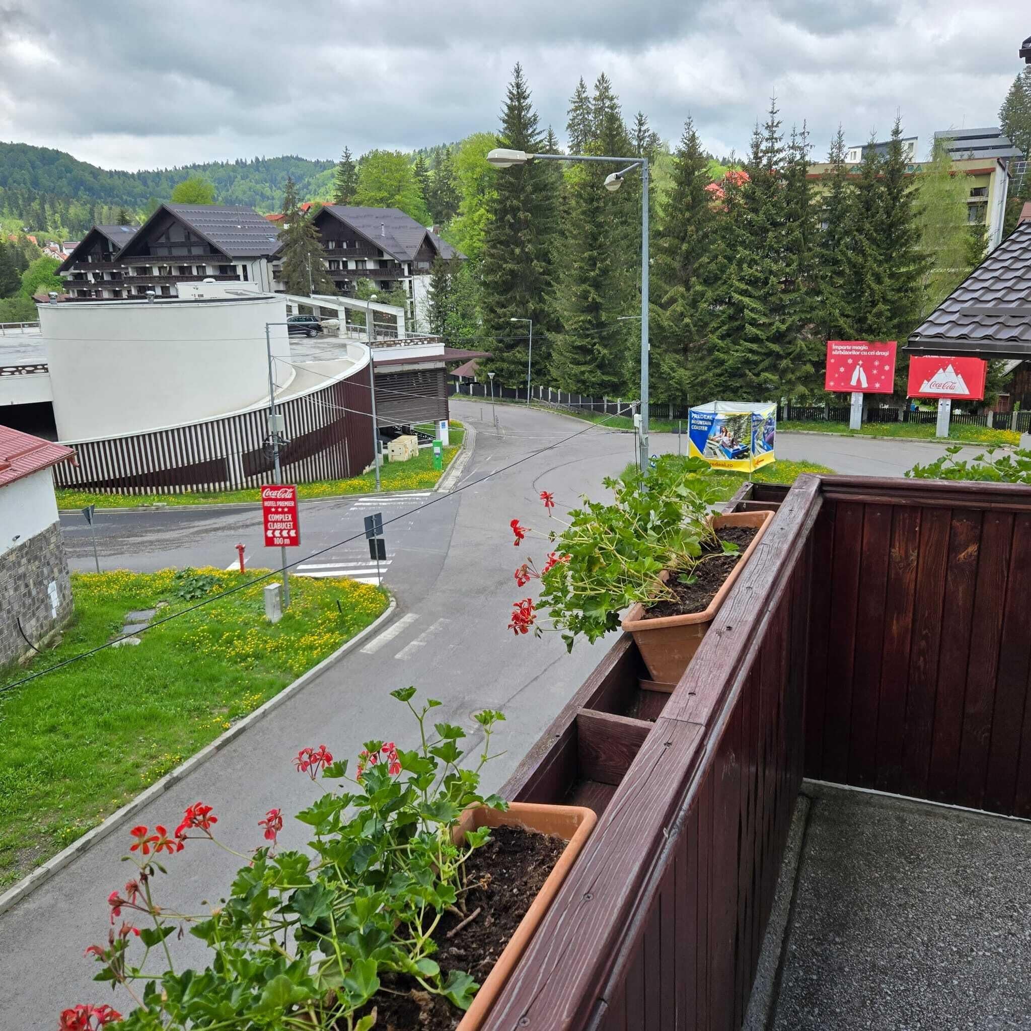 A hotel with a modern design, a parking area, and a view of the surrounding greenery and mountains.