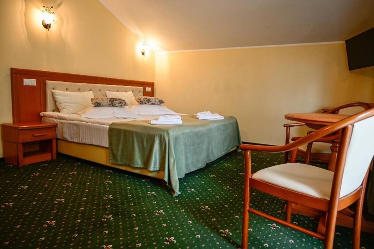 A hotel room with a bed, a chair, a small table, and a television.