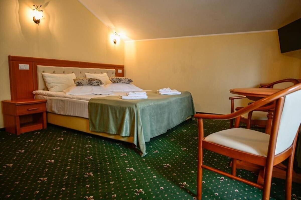 A hotel room with a bed, a chair, a nightstand, and a wall-mounted TV.