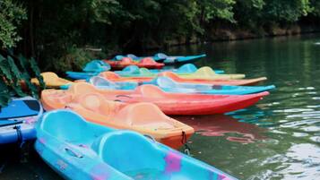 Une rangée de kayaks aux couleurs vives est amarrée au bord d’une rivière paisible.